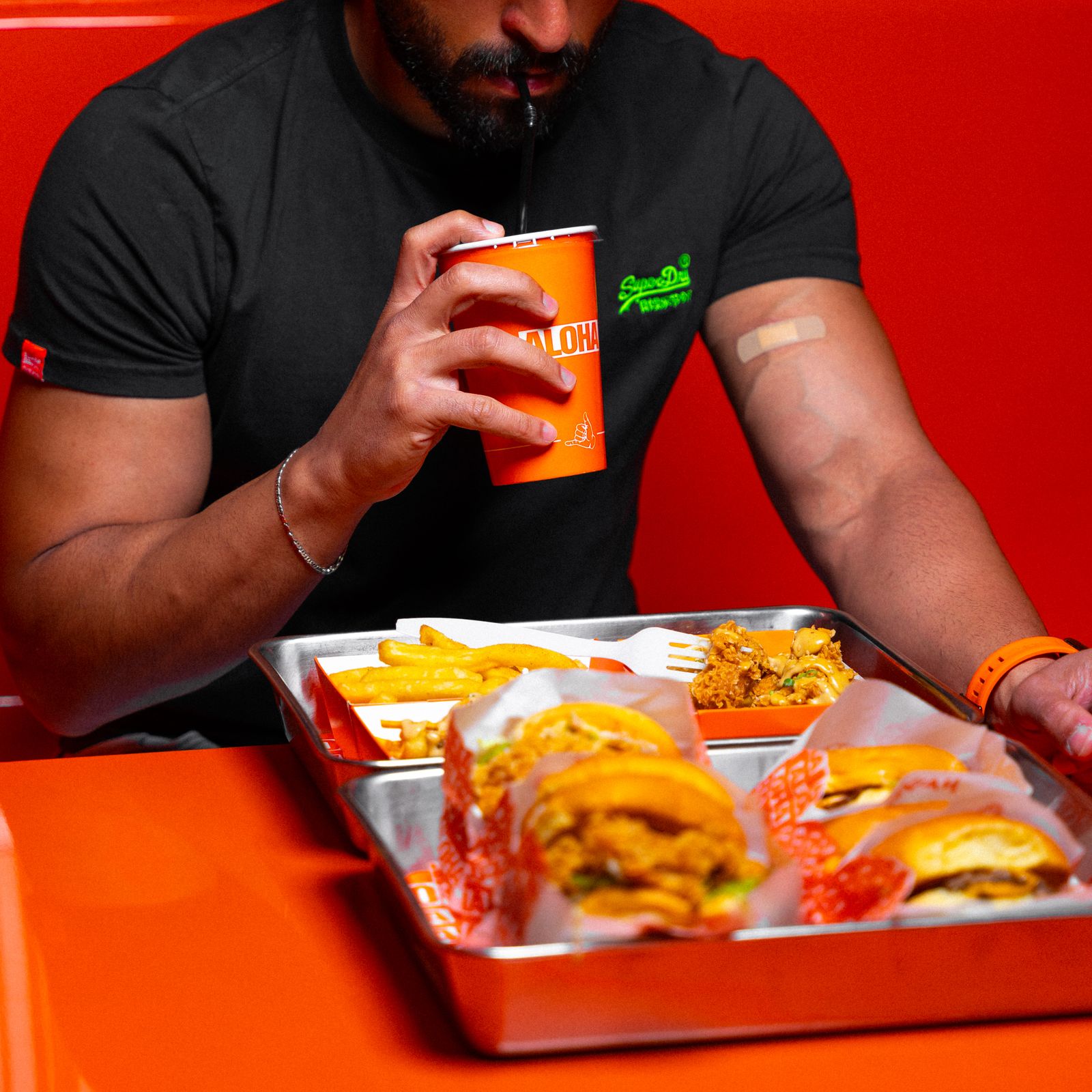 A man enjoys a fast food meal with burgers, fries, and a drink at a restaurant.